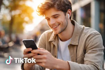 Молодой пользователь смотрит TikTok на смартфоне и улыбается, мобильное приложение и социальные сети.